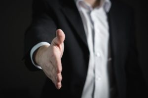 School administrator extending hand for an introductory handshake at the beginning of a manifestation determination review meeting